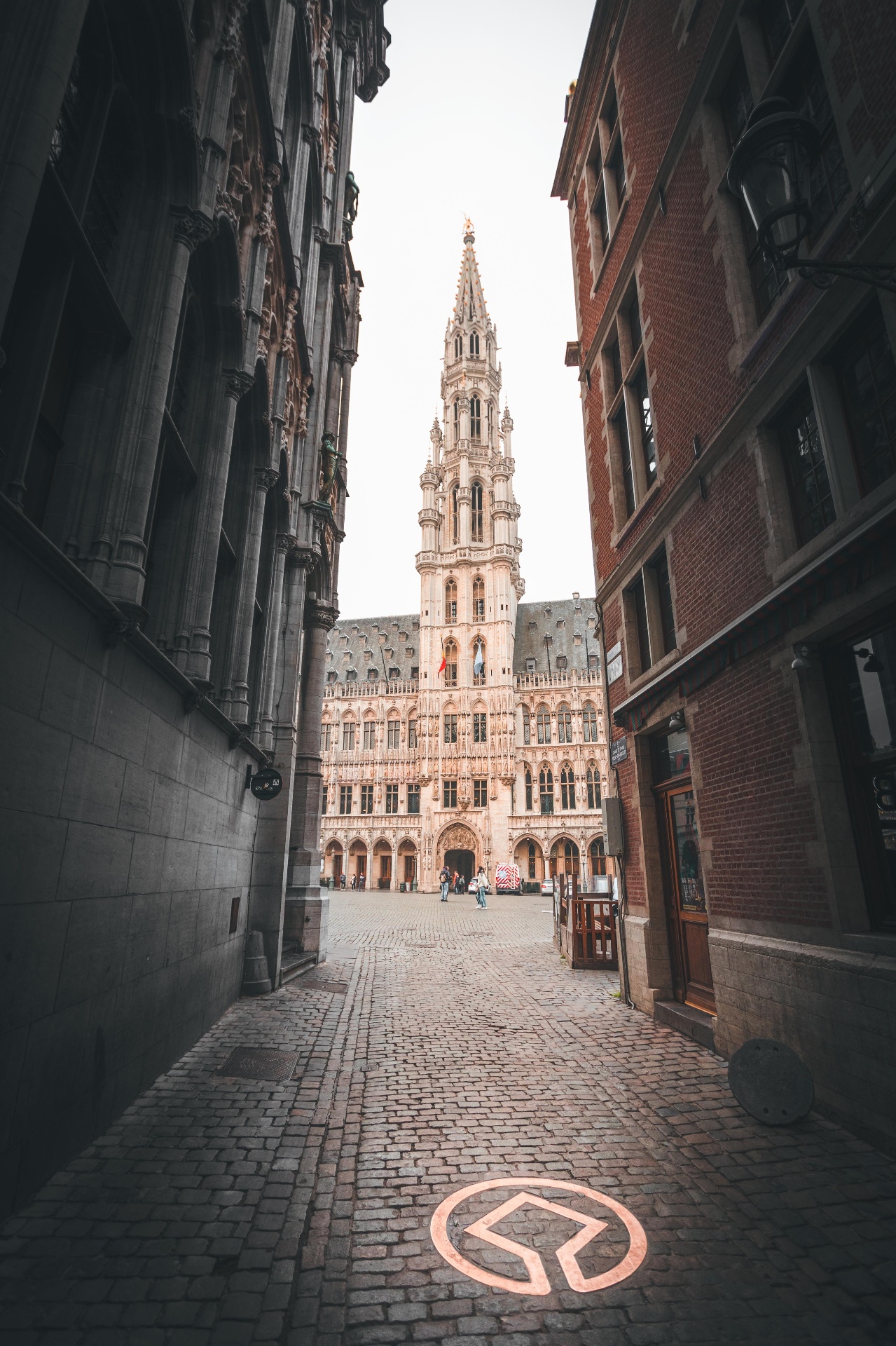 Hôtel de Ville de Bruxelles vu depuis une ruelle pavée de la Grand-Place.
